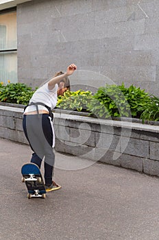 Adult girl skateboarding in the street. Female skateboarder learning no comply trick. Teenager riding a skateboard