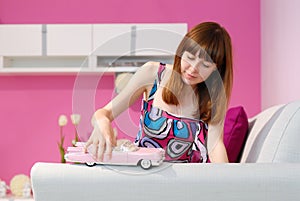 An adult girl and a toy car in a children`s pink room on the sofa