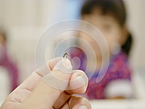 Adult hand catching a mosquito on a defocus background of little baby girl