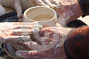 adult hand fed baby's hands to work with a potter's wheel