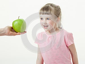 Adult hand giving a green apple for pretty little girl