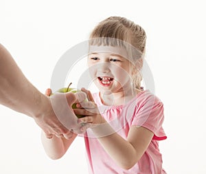 Adult hand giving a green apple for pretty little girl