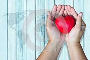 Adult hands holding red heart on map wooden plank with background insurance top view, caring family insurance, health care, love