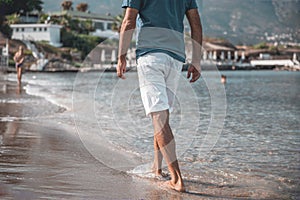 Adult handsome man walking barefoot on the water along the seashore. Famous North Cyprus Beach Background