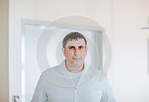 Adult handsome white doctor posing at white operation room. Copy space