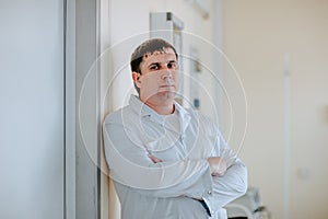 Adult handsome white doctor posing at white operation room. Copy space