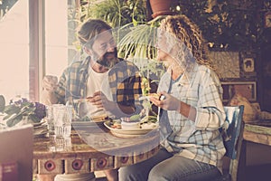 Adult happy couple eating brunch together sitting inside the cae bar restaurant. Casual people enjoynig food. Man and woman photo