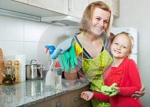 Adult mom and little kid cleaning at kitchen photo