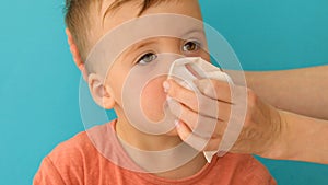 Adult helps child to blow and wipe his running nose