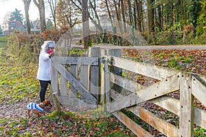 Adult hiker opening gate to exit Dutch nature reserve Geleenbeekdal