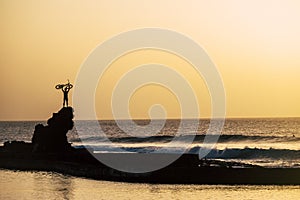 Adult holding on his arms up a bike at the beach on a big rock - freedom concept and lifestyle - great sunset - ocean and sea with