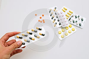 Adult holds pills in his hand on a background of a pile of medical pills. Pills in a plastic bag.