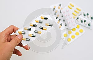 Adult holds pills in his hand on a background of a pile of medical pills. Pills in a plastic bag.