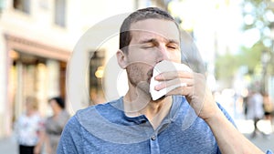 Adult ill man sneezing using a tissue in the street