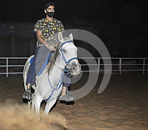 An Adult Indian male riding a white horse