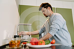 Adult indian man washing vegetables to cook salad