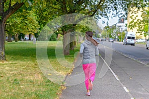 Adult jogger running along street next to park