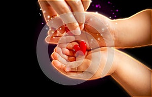 Adult and little child holding red hearts, and close up isolated on black background