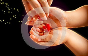 Adult and little child holding red hearts, and close up isolated on black background