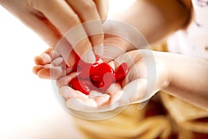 Adult and little child holding red hearts, and close up isolated on white background