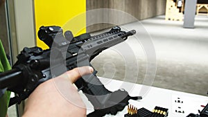 Adult loading an assault rifle at a shooting range.