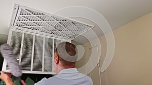 Adult Male Cleaning Dusting Air Duct Vent Grid Inside and Exterior