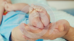 An adult male hand holding a small baby feet.