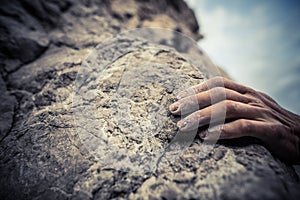 Adult male handholding on to a rock