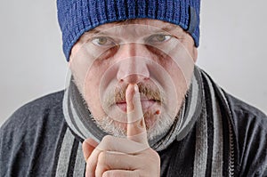 A adult male holds his finger to his lips. A gesture of silence