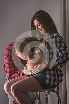 Adult male kisses the belly of a pregnant wife