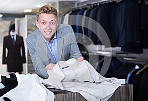 Adult male purchaser in jacket choosing shirt