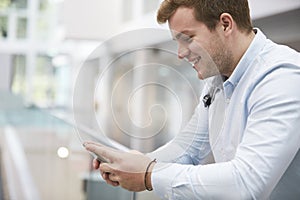 Adult male student using smartphone in university, close up