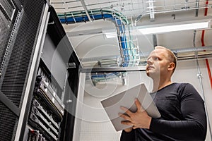 Adult Male Technician Holding Digital Tablet and Analysing Servers in Datacenter