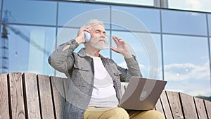 Adult male with wireless headset working on laptop outdoors