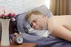 An adult man 40-45 years old is fast asleep bed without hearing a loud