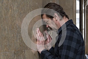 an adult man 40-50 years old with a beard, leaning against the wall. Concept: stressful situation, dismissal and troubles at work,