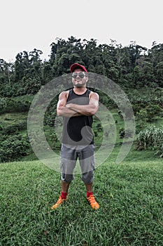 Adult man with arms crossed in the middle of a landscape full of green vegetation and trees on a cloudy morning