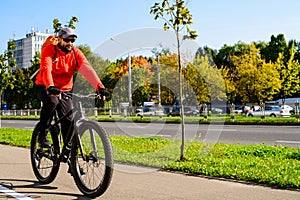 Adult man with backpack riding a bicycle in the city street. Car