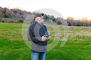 An adult man with a beard launches a drone into the sky. Holds the remote control and watches the flight