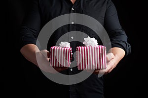 Adult man in a black shirt holds in his hand a stack of paper-wrapped gifts