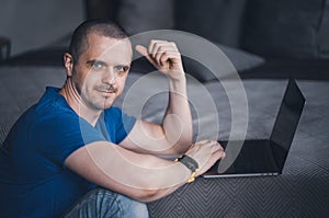 Adult man in blue t-shirt working on laptop