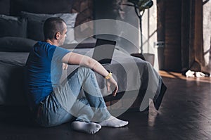 Adult man in blue t-shirt working on laptop