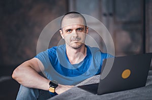 Adult man in blue t-shirt working on laptop