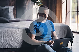 Adult man in blue t-shirt working on laptop