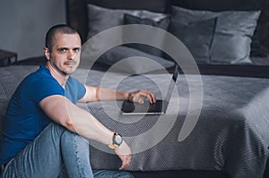 Adult man in blue t-shirt working on laptop