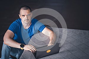 Adult man in blue t-shirt working on laptop