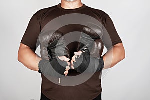 Adult man in brown sport uniform holds a pair of brown vintage casual boxing gloves