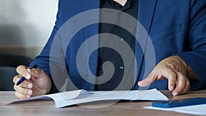 An adult man in a business suit, sitting at a table with a pen, fills out an agreement or order form. Concept of concluding an