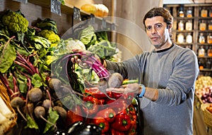 Adult man buyer chooses beets in shop