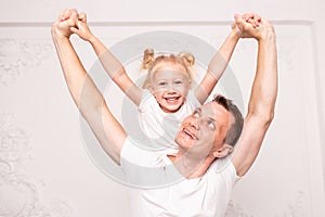 Adult man carries his daughter on his back on father`s Day